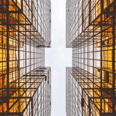 Two amber glass towers with grid scaffolding facing the sky